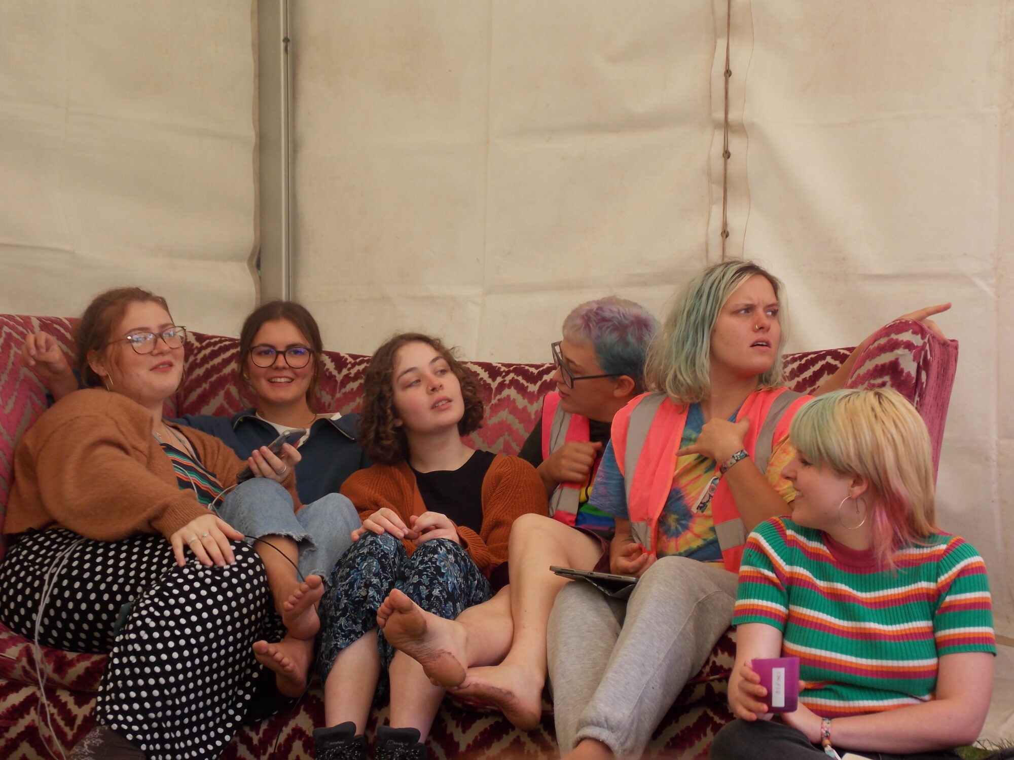 A group of young people sitting on a sofa in a marquee